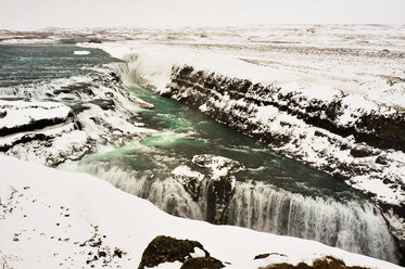 Blick von oben auf einen Wasserfall inmitten schneebedeckter Berge - CAVF36765