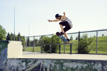 Junger Mann fährt mit dem Skateboard auf einem Geländer - CAVF36998