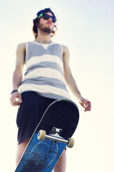 Low section of young man with skateboard - CAVF36999