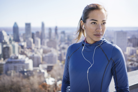 Frau hört Musik mit Stadtlandschaft im Hintergrund, lizenzfreies Stockfoto