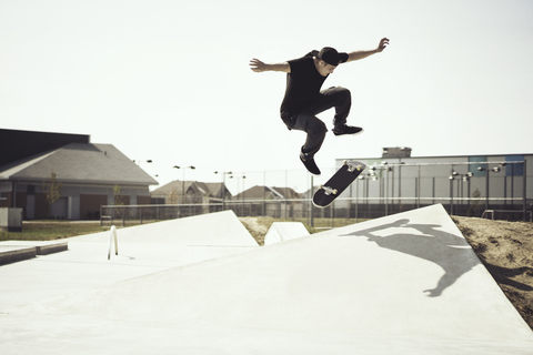 Junger Mann vollführt Stunts auf dem Skateboard, lizenzfreies Stockfoto