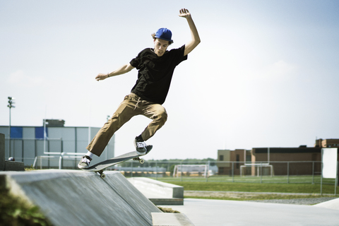 Junger Mann vollführt Stunts auf dem Skateboard, lizenzfreies Stockfoto