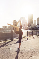 Frau übt Yoga in der Stadt bei Sonnenaufgang - CAVF37030