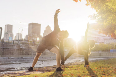 Couple practicing yoga in park during sunrise - CAVF37036