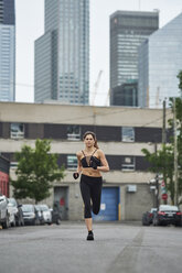 Sporty woman jogging on street in city - CAVF37042