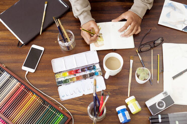 Cropped image of male illustrator making painting at desk in creative office - CAVF37094