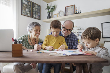 Happy grandparents looking at grandsons making drawings at home - CAVF37134