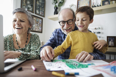 Fröhliche Großeltern mit Enkel, der zu Hause malt - CAVF37137