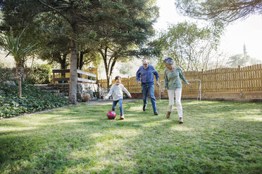 Großeltern spielen Fußball mit Enkel im Garten - CAVF37144