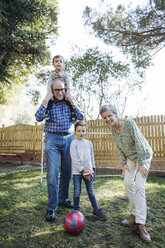 Portrait of happy grandparents with grandsons playing soccer at yard - CAVF37145