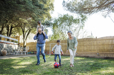 Großeltern und Enkel in voller Länge beim Fußballspielen im Garten - CAVF37146