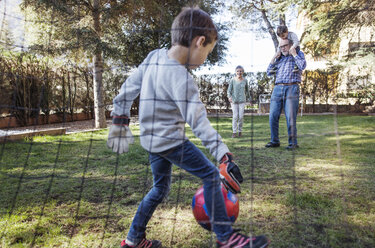 Junge spielt Fußball mit Familie im Garten - CAVF37150