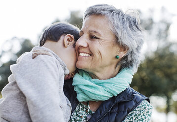 Happy senior woman carrying grandson in park - CAVF37166