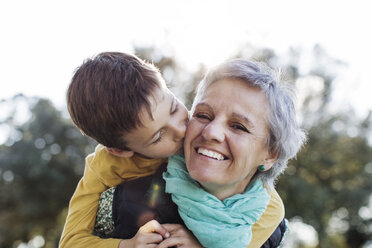 Loving grandson kissing grandmother in park - CAVF37167