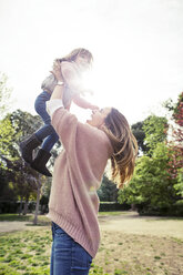 Side view of cheerful woman picking daughter at park - CAVF37175