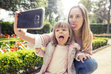 Mutter und Tochter strecken die Zunge heraus, während sie ein Selfie im Park machen - CAVF37177