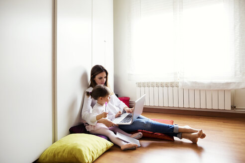 Mutter und Tochter benutzen Laptop zu Hause - CAVF37189