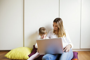 Glückliche Mutter und Tochter benutzen einen Laptop zu Hause - CAVF37190