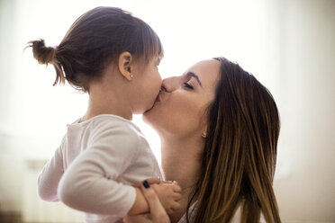 Side view of loving mother kissing daughter at home - CAVF37192