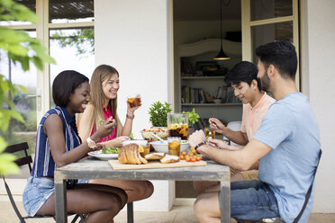 Glückliche Freunde beim Mittagessen am Tisch im Freien - CAVF37219