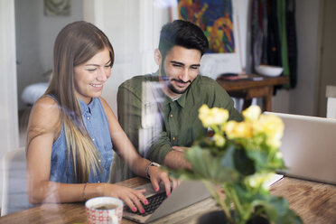 Happy couple using laptop at home - CAVF37234