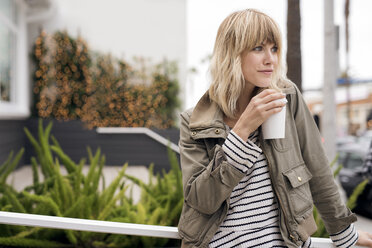 Thoughtful young woman drinking coffee outdoors - CAVF37251