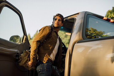 Man looking away while entering into pick-up truck - CAVF37263