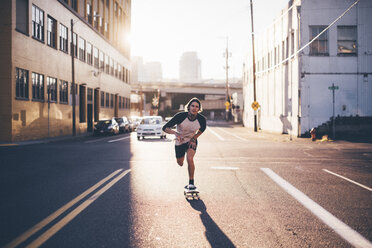 Porträt eines Mannes, der auf einer Straße in der Stadt Skateboard fährt, gegen den Himmel an einem sonnigen Tag - CAVF37277
