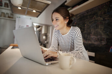 Happy woman working on laptop at table - CAVF37283