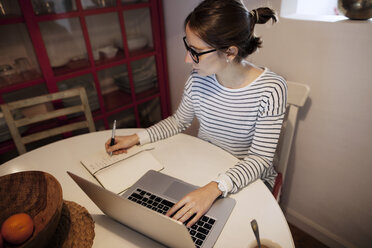 Frau plant bei der Arbeit am Laptop zu Hause - CAVF37296