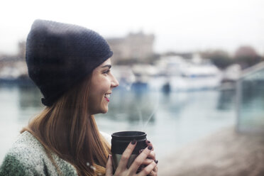 Side view of happy woman enjoying coffee at harbor - CAVF37300