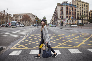 Portrait of woman carrying bouquet in bag while walking on city street - CAVF37302