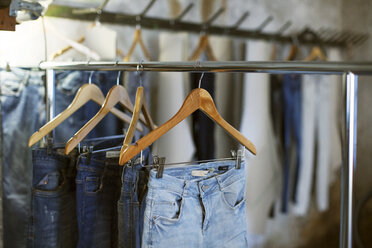 Verschiedene Jeans hängen in der Werkstatt auf Kleiderbügeln - CAVF37321