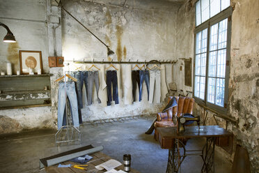 Jeans hanging on rack in old workshop - CAVF37323