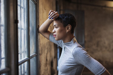 Side view of thoughtful businesswoman looking through window at workshop - CAVF37328