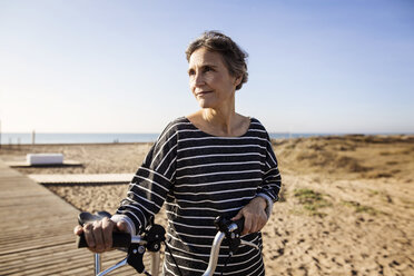 Frau mit Fahrrad am Strand gegen klaren Himmel - CAVF37332