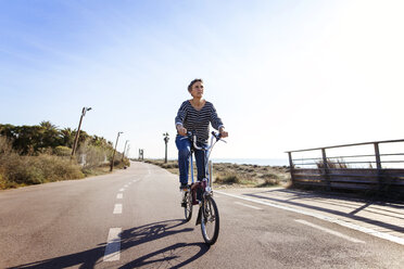 Woman cycling on road against clear sky - CAVF37338