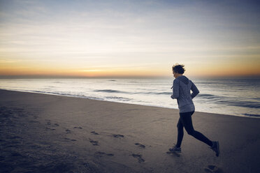 Frau joggt am Strand gegen den Himmel - CAVF37357