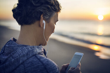 Nahaufnahme einer Frau, die am Strand gegen den Himmel telefoniert - CAVF37361