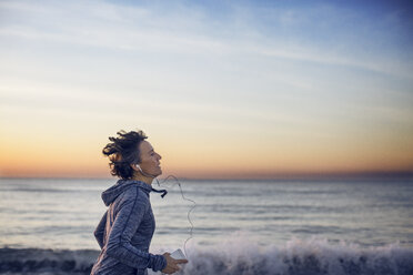 Frau joggt am Strand gegen den Himmel - CAVF37365