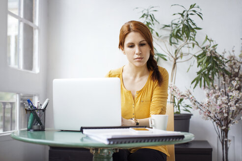 Nachdenkliche Geschäftsfrau arbeitet am Laptop am Tisch im Büro - CAVF37399