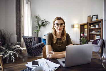 Portrait of confident businesswoman sitting at table with laptop in office - CAVF37425