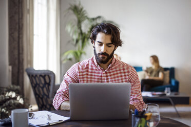 Kreativer Geschäftsmann arbeitet am Laptop, während er am Tisch im Büro sitzt - CAVF37428