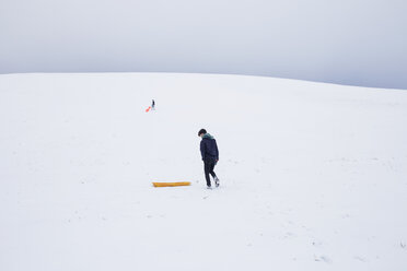 Männer mit Schlitten auf schneebedeckten Bergen gegen den Himmel - CAVF37466