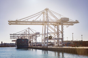Low angle view of cranes at commercial dock against clear sky - CAVF37503
