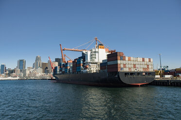 Container ship moored at commercial dock against clear blue sky - CAVF37504