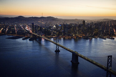 Aerial view of Bay Bridge and illuminated cityscape during sunset - CAVF37524