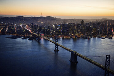 Luftaufnahme der Bay Bridge und beleuchtete Stadtlandschaft bei Sonnenuntergang - CAVF37524