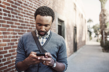 Man text messaging while standing on sidewalk - CAVF37550