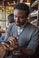 Junger Mann schreibt eine SMS, während er im Café sitzt - CAVF37557